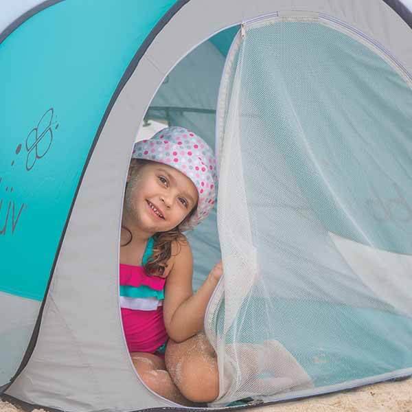 Child peeking out from a tent with a blue interior